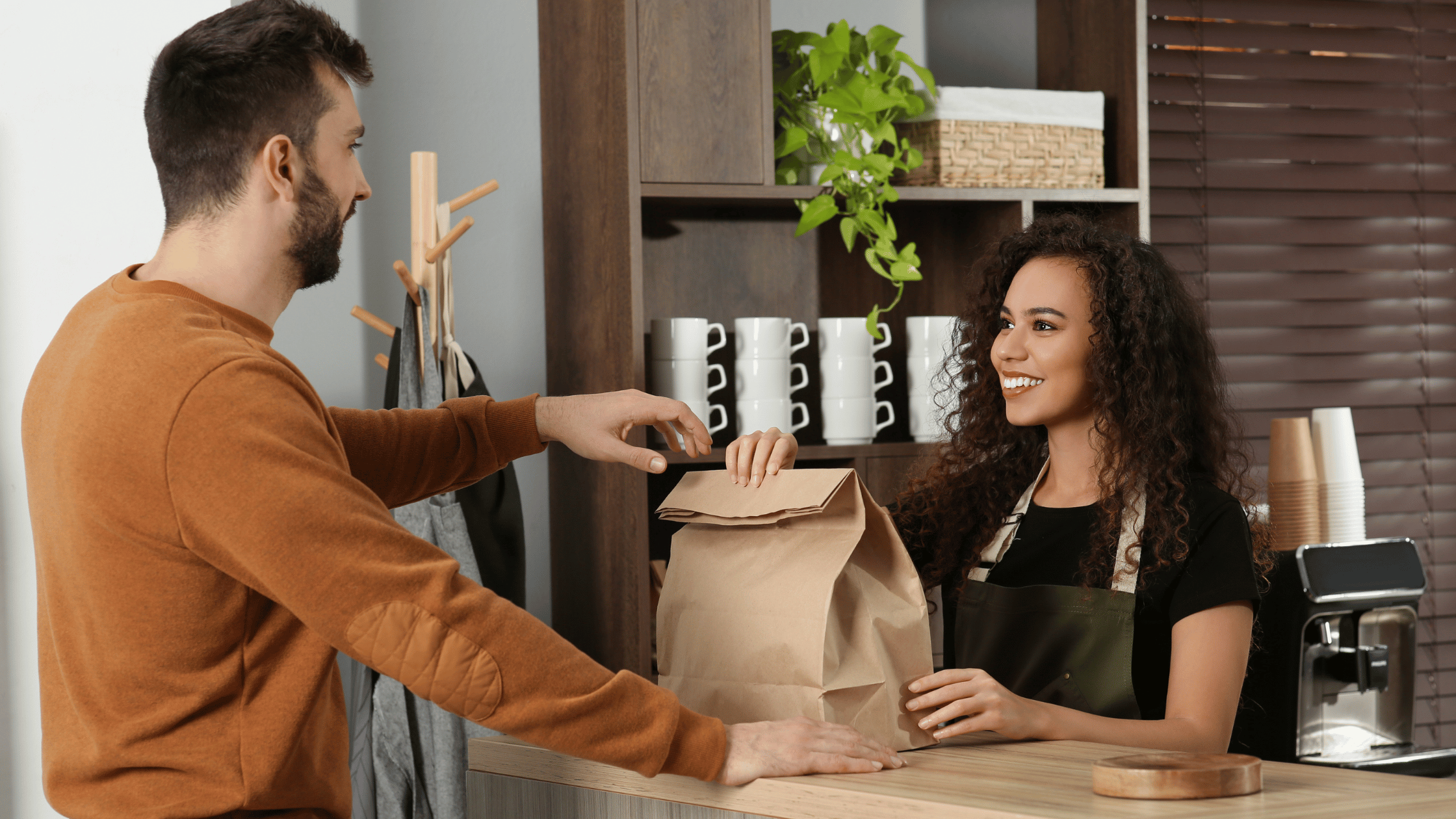 Customer collecting pickup order from restaurant worker.