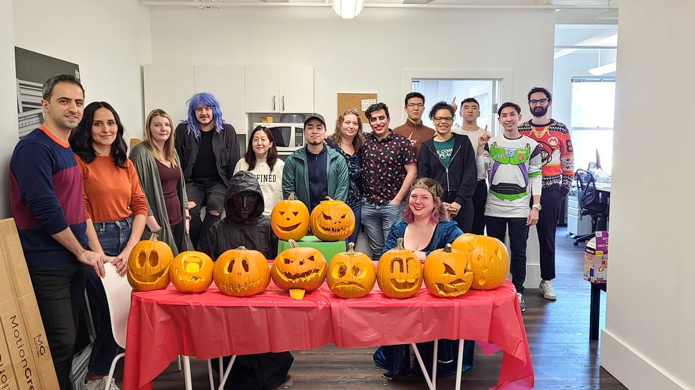 The Craver team beside a table of carved pumpkins in the office