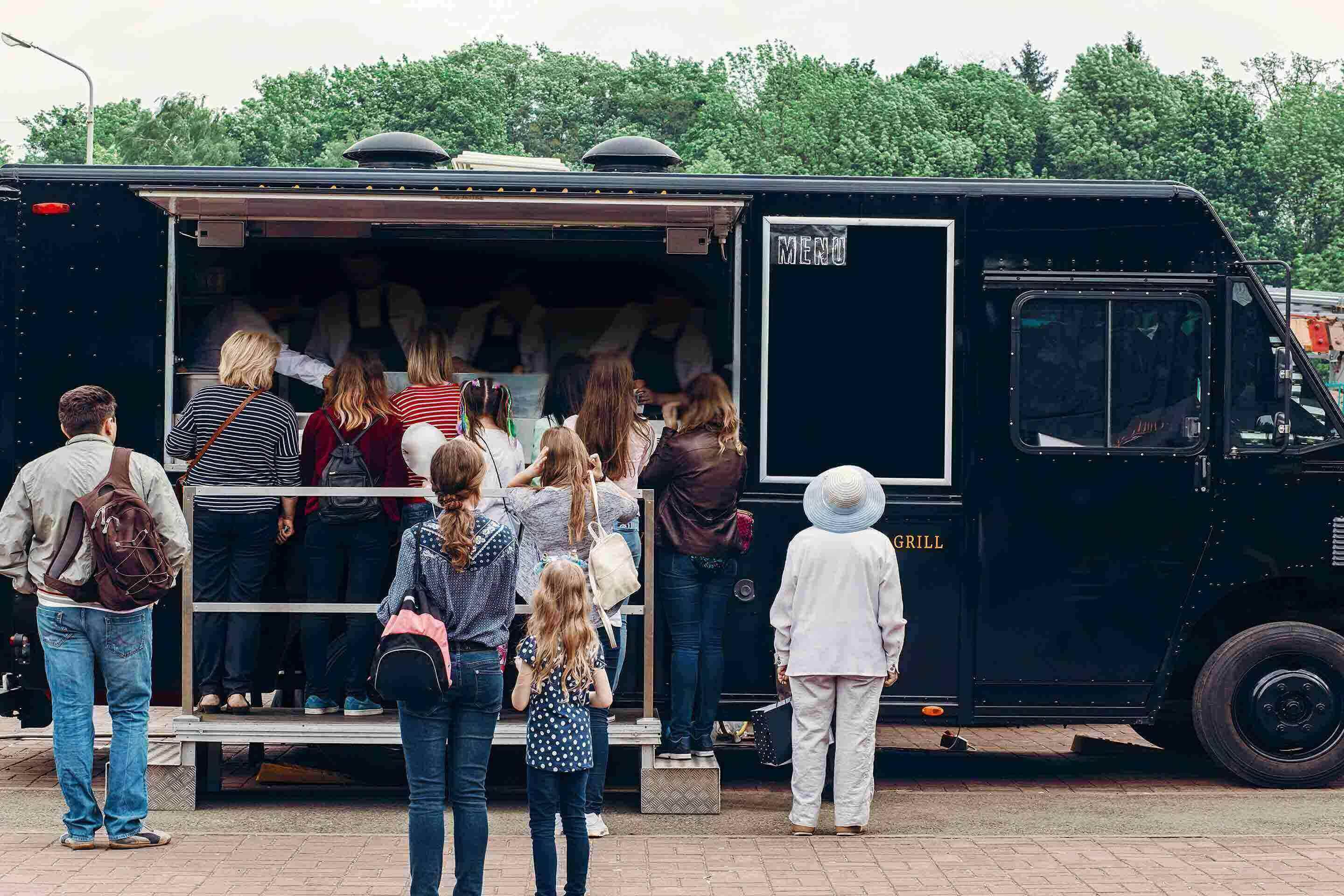 A line up outside a black food truck