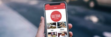 A hand holding a phone with the Railtown app open