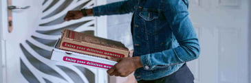 A woman delivering pizza to a house door. 