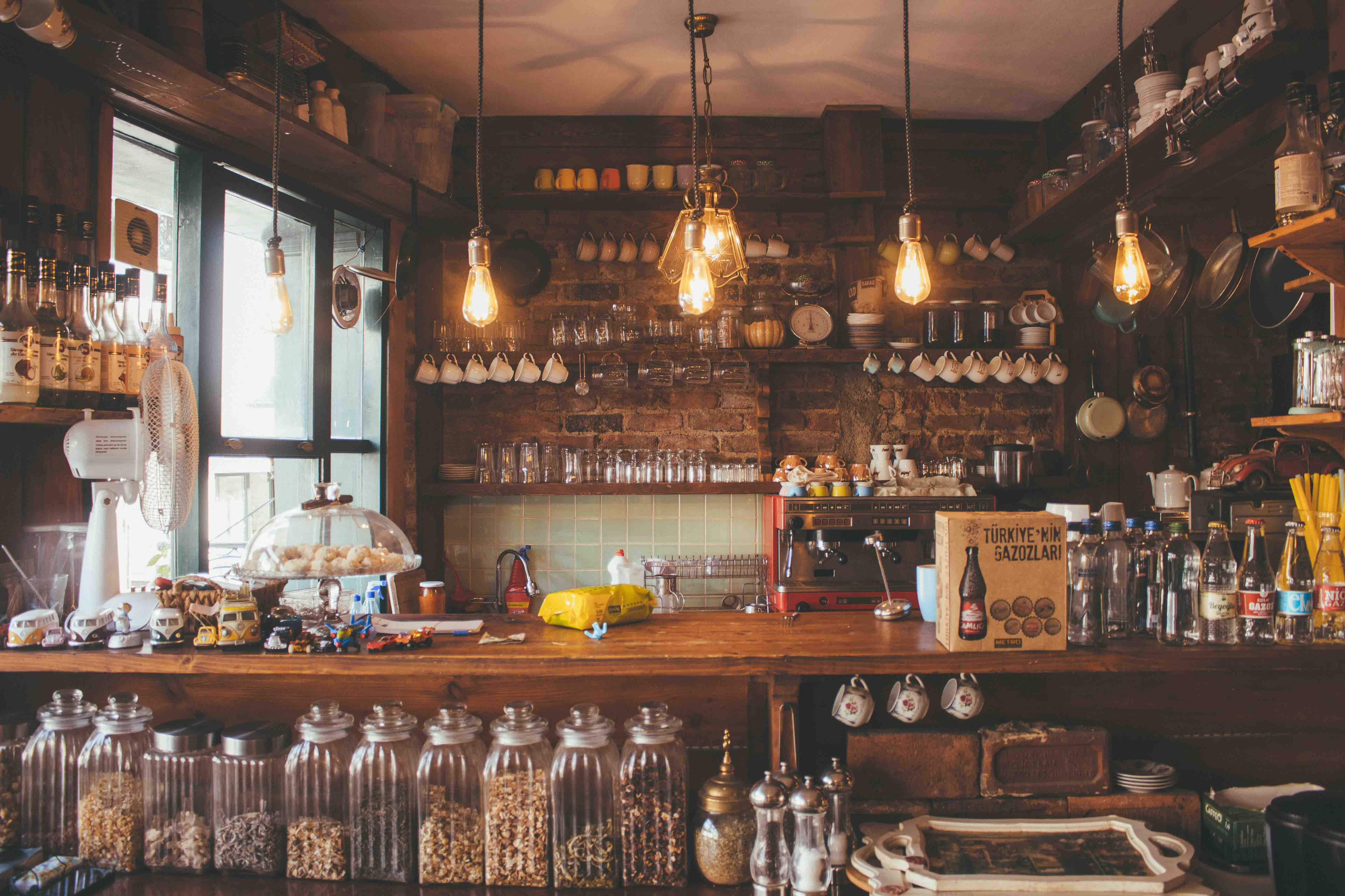 A coffee shop bar with spices, baked goods, and syrups on the counter