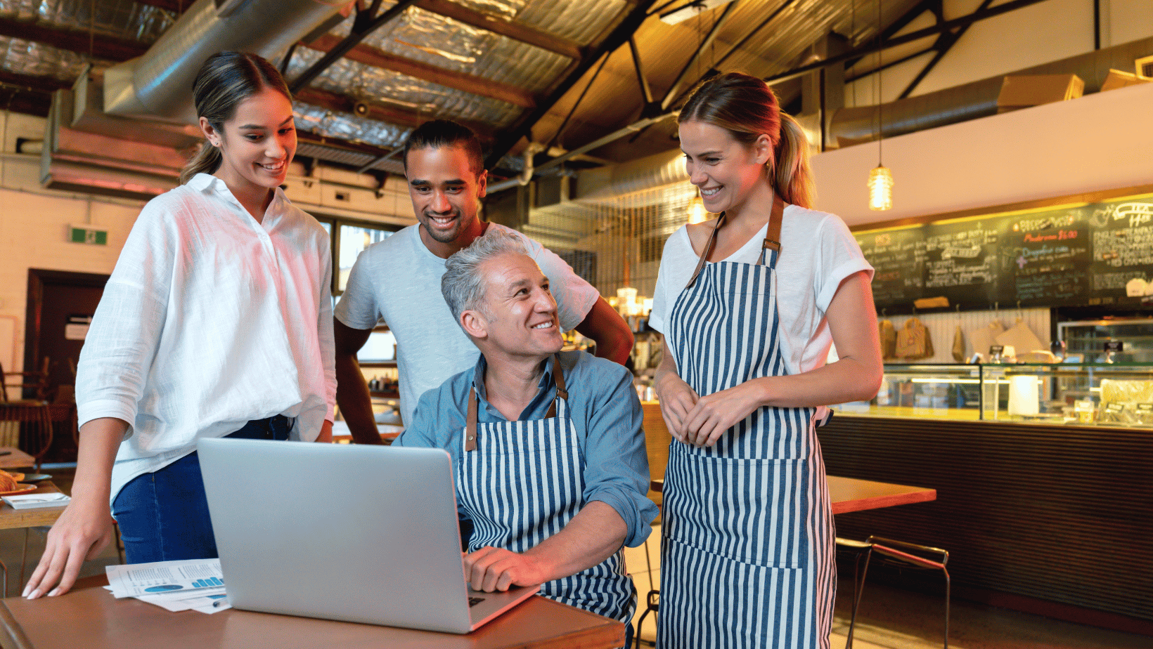 Restaurant owner showing sharing information on his laptop with staff members. 