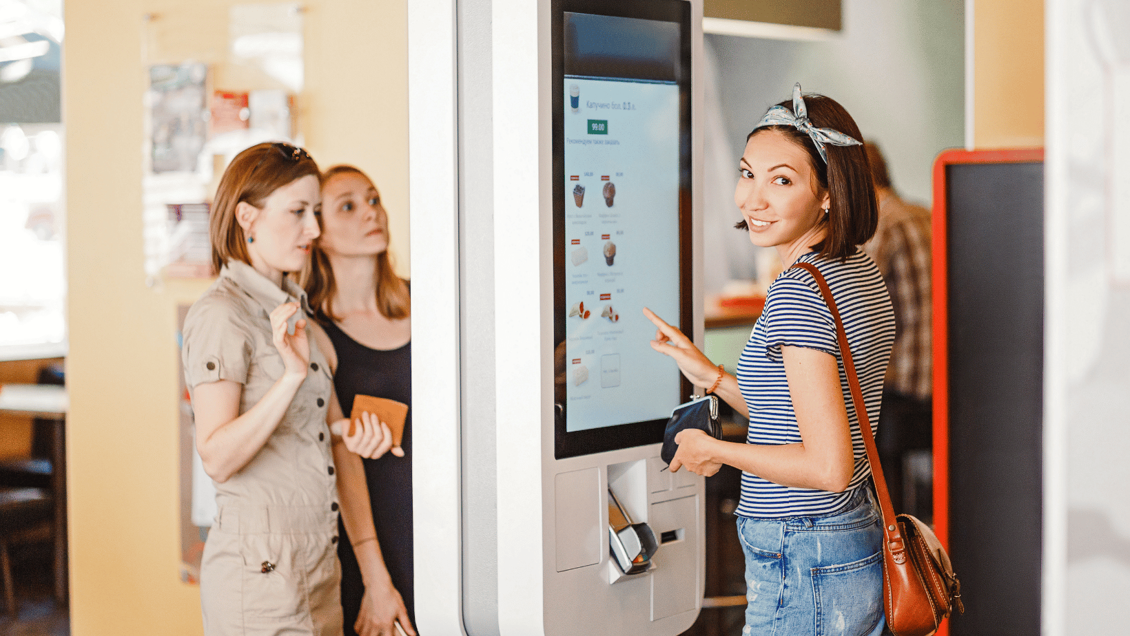 Friends ordering at a touch screen self service terminal in fast-food restaurant