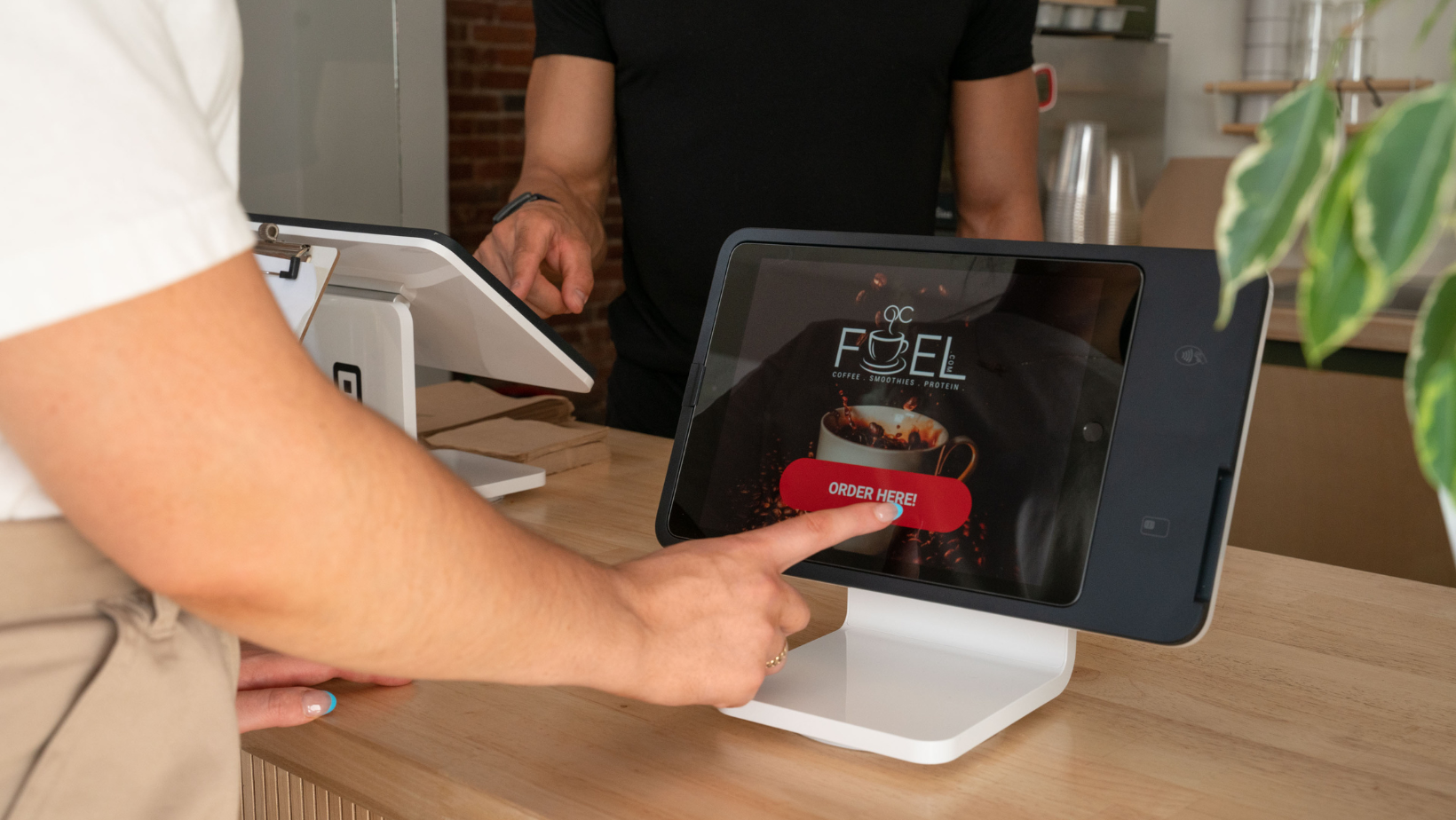 Customers ordering on self-serve kiosks at a coffee shop. 