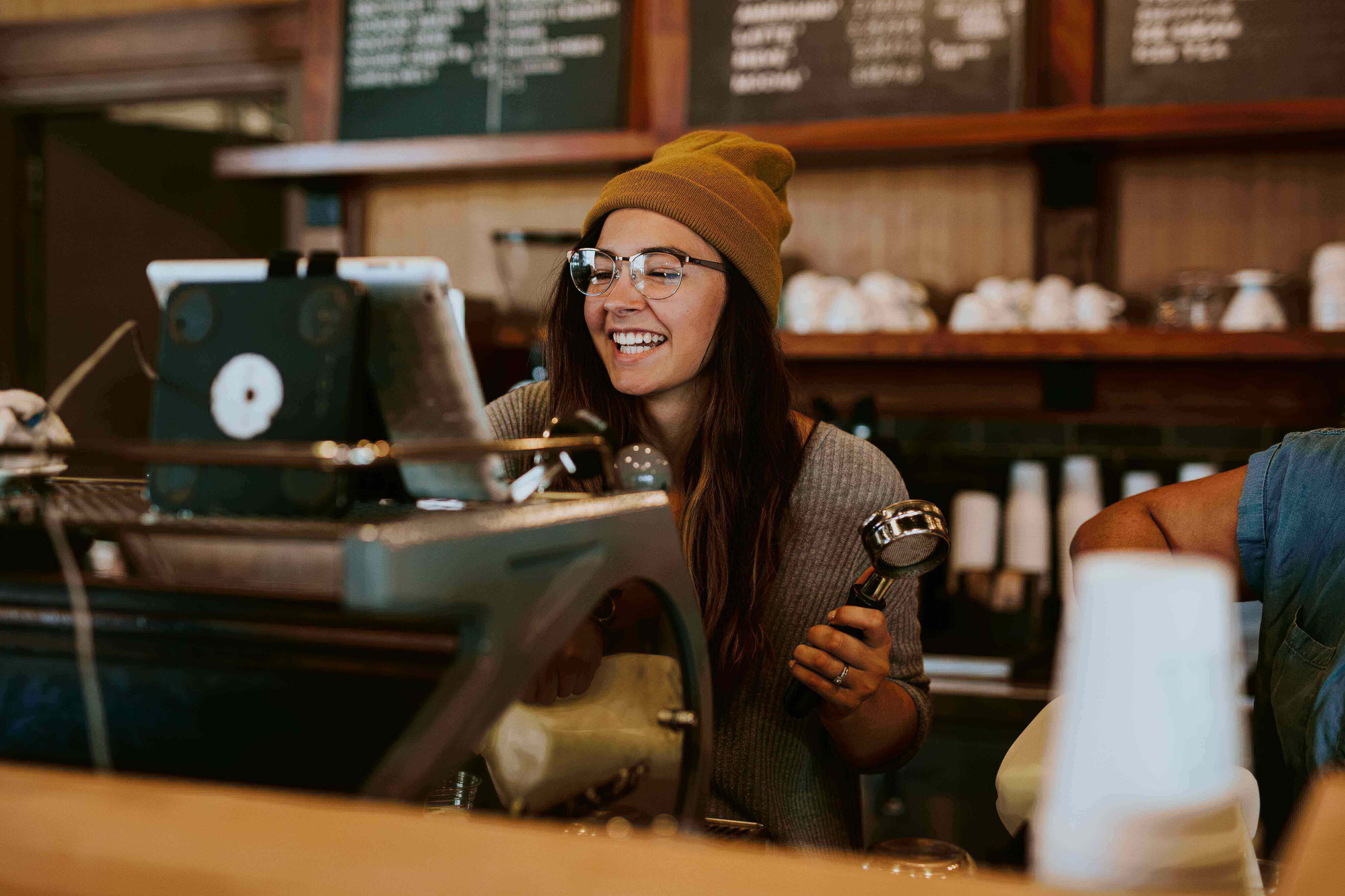 A woman making an espresso behind the counter of a coffee shop