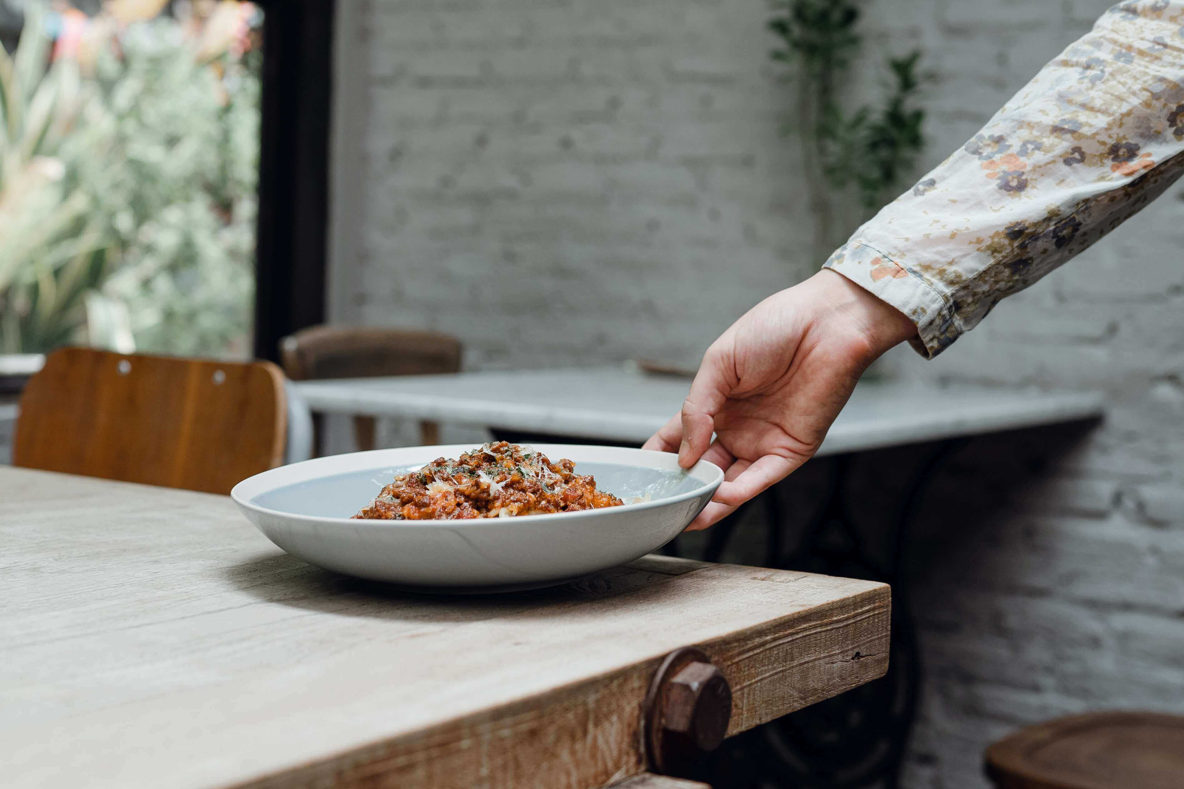 A person setting down a plate of pasta