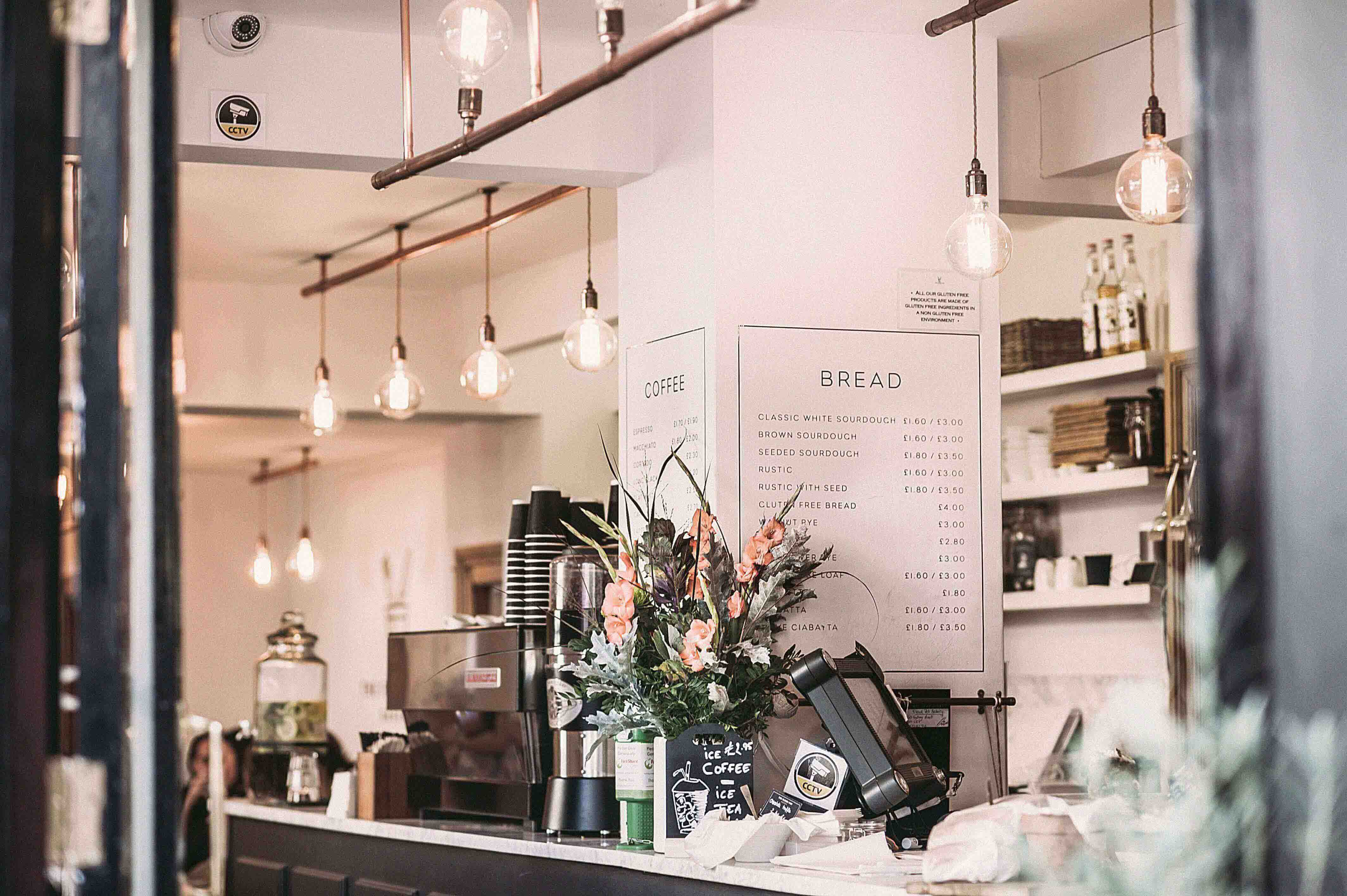 A bright coffee shop with flowers at the till