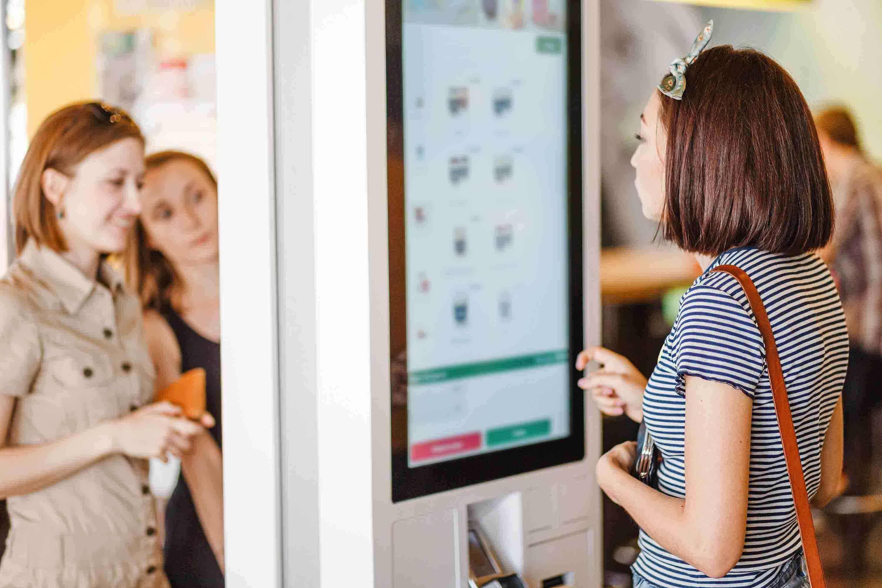 A person entering an order on a giant kiosk