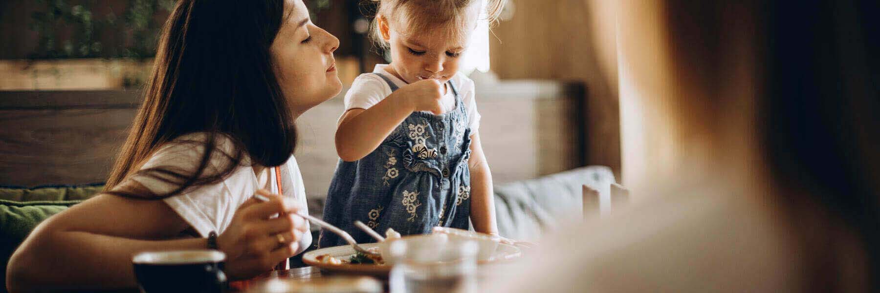 a woman and her child eating at a restaurant