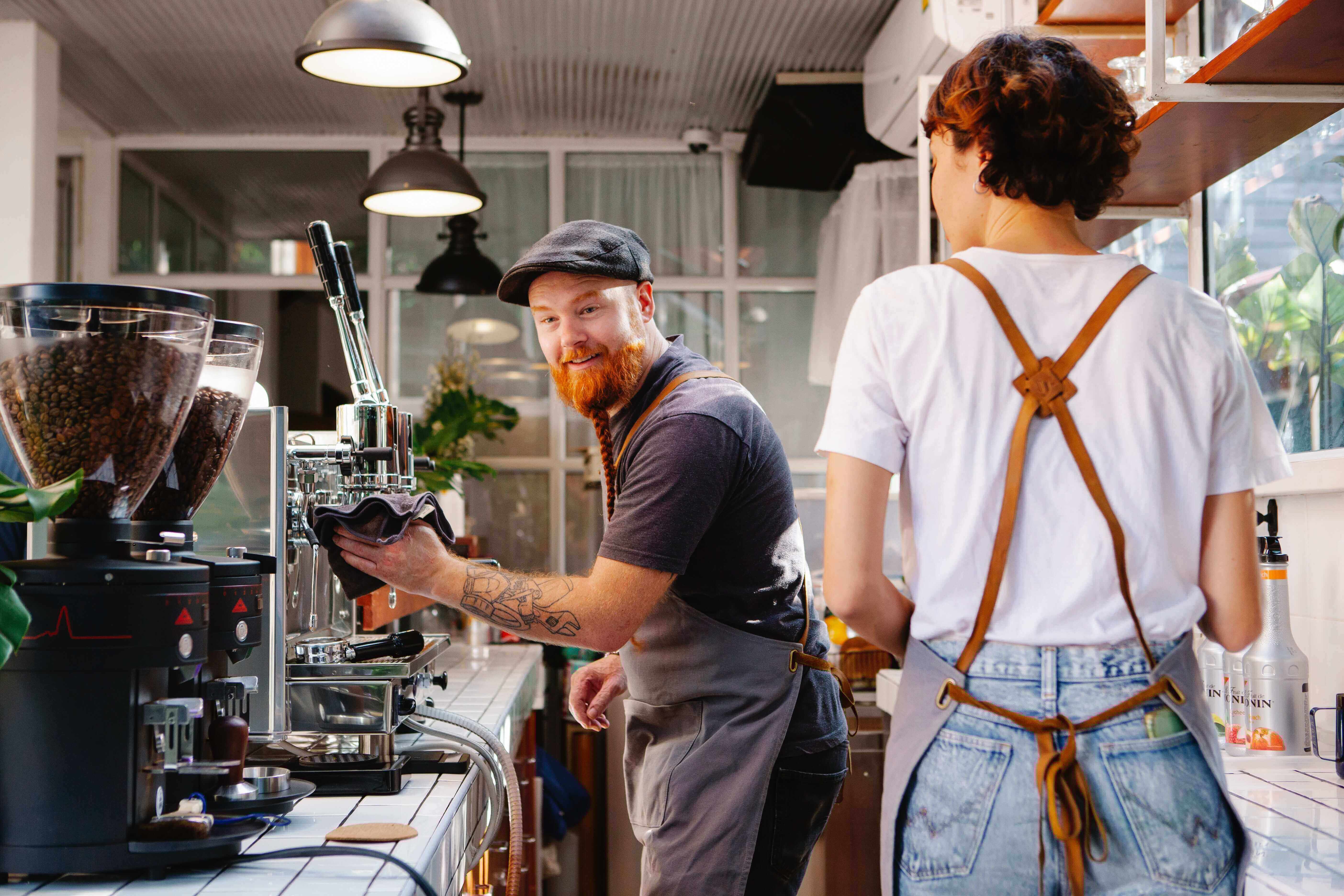 A man making as espresso while talking to a coworker